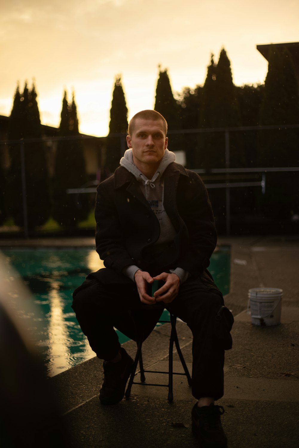 a man sitting on a chair next to a pool