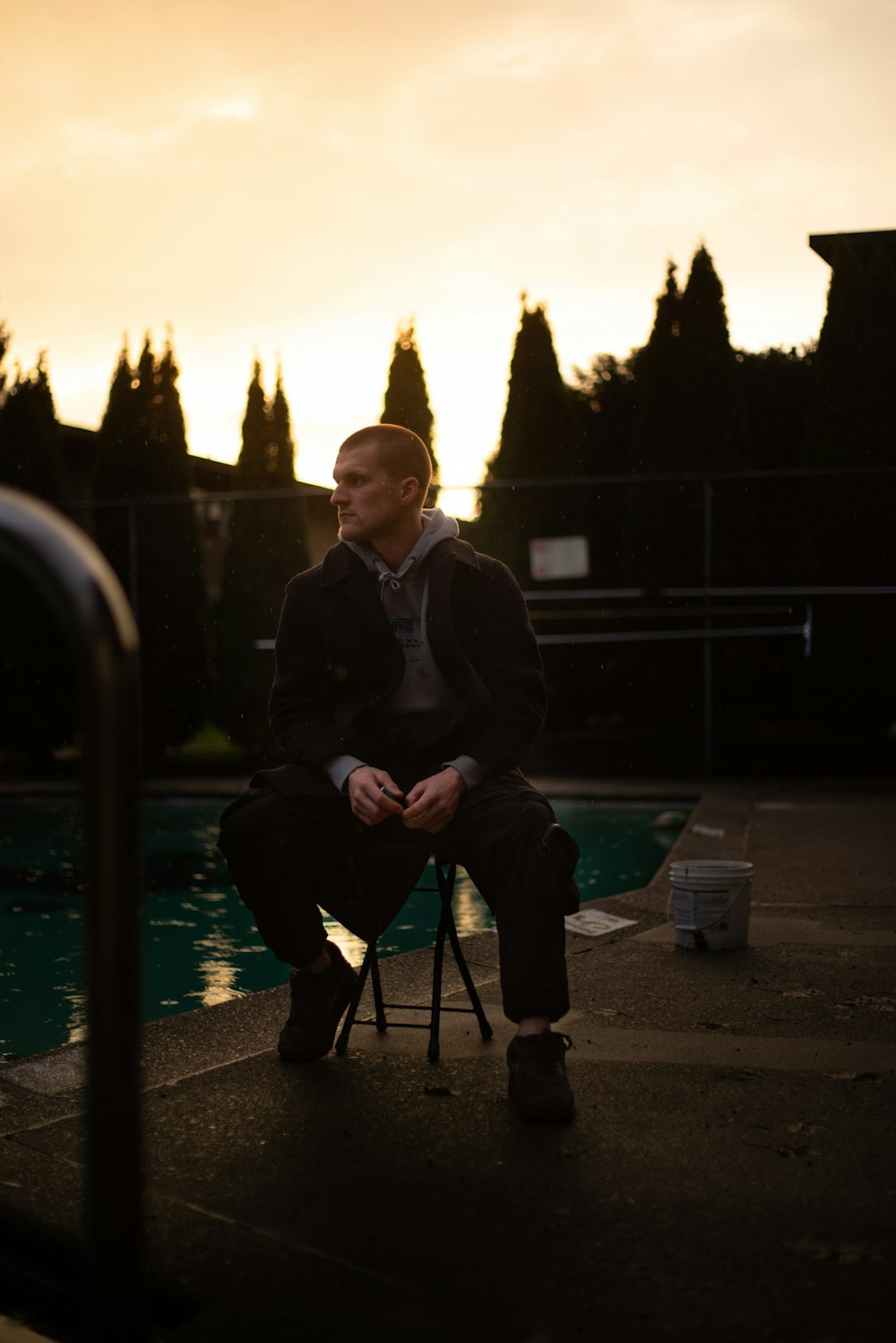 a man sitting on a chair in front of a pool
