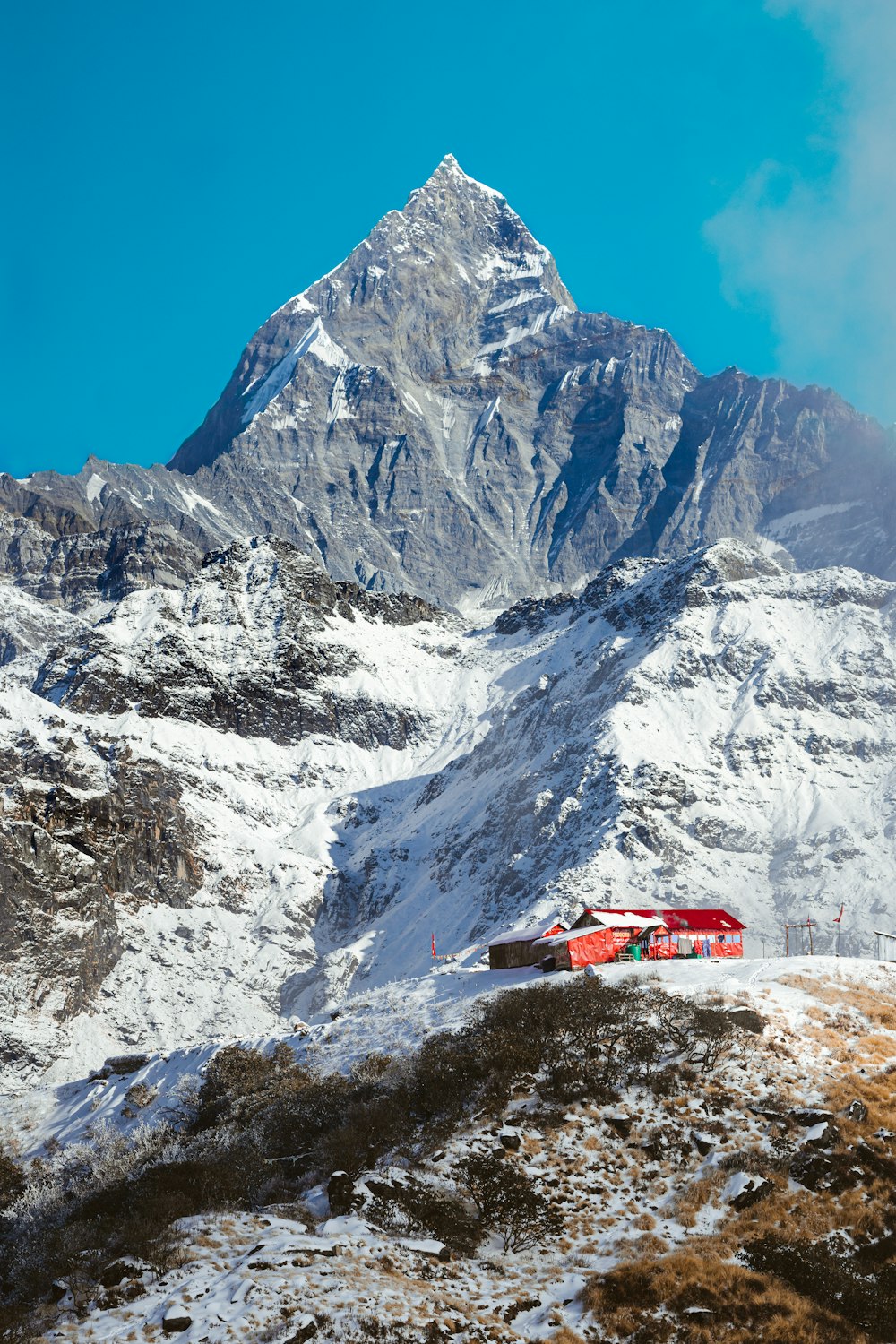a snow covered mountain with a red house in the foreground