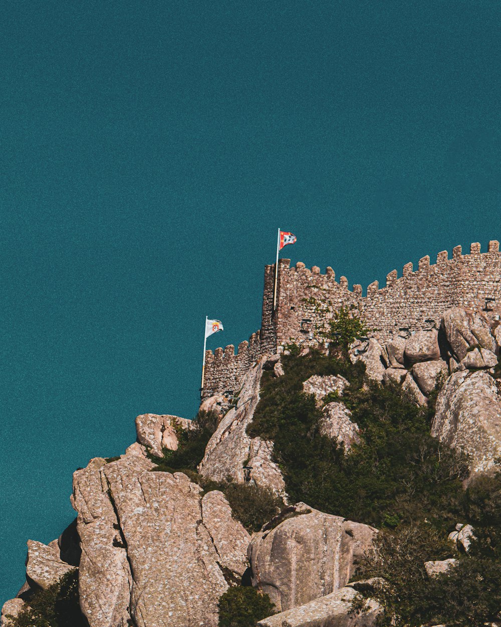 un château au sommet d’une montagne avec un drapeau dessus