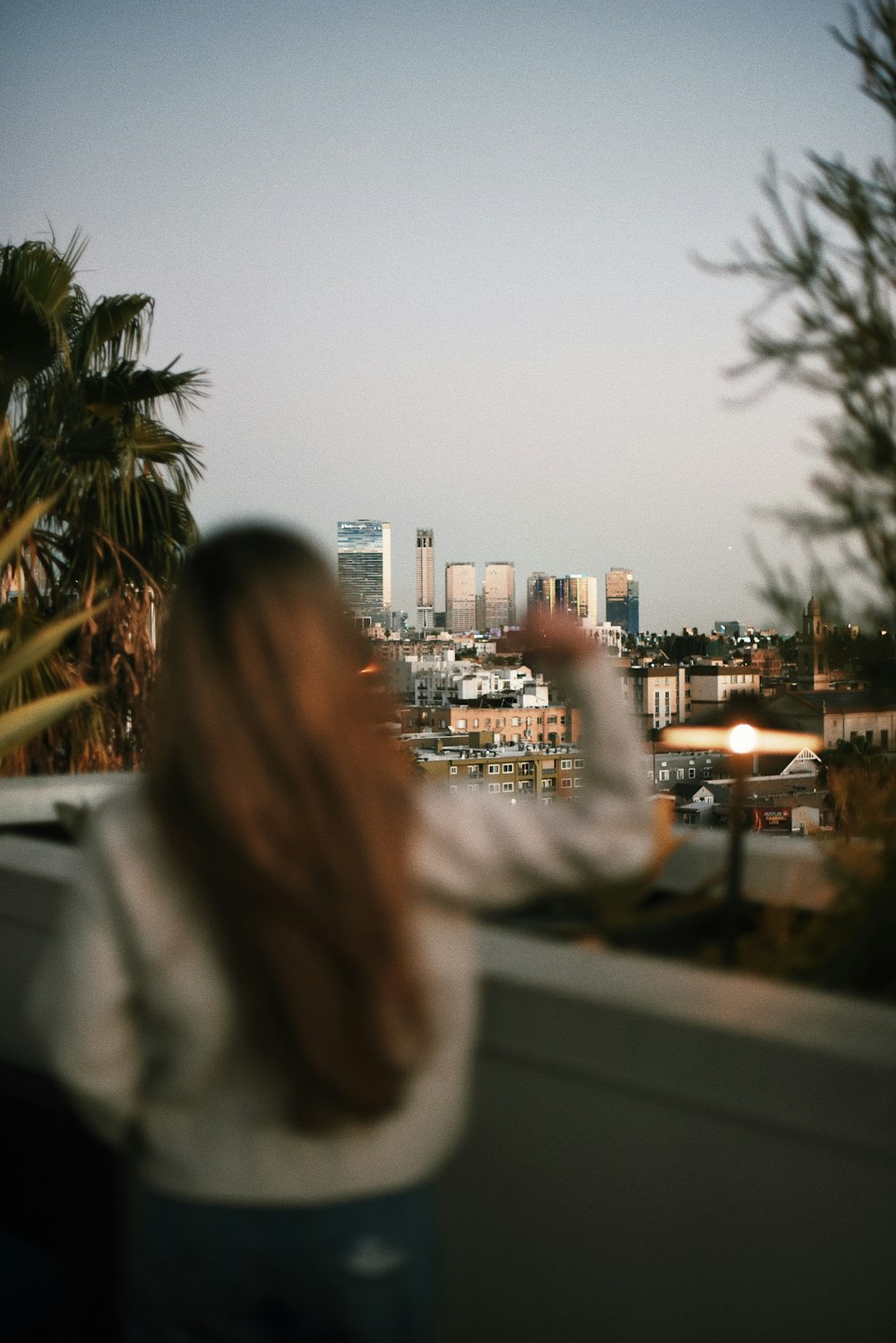 a woman standing on top of a balcony next to a palm tree