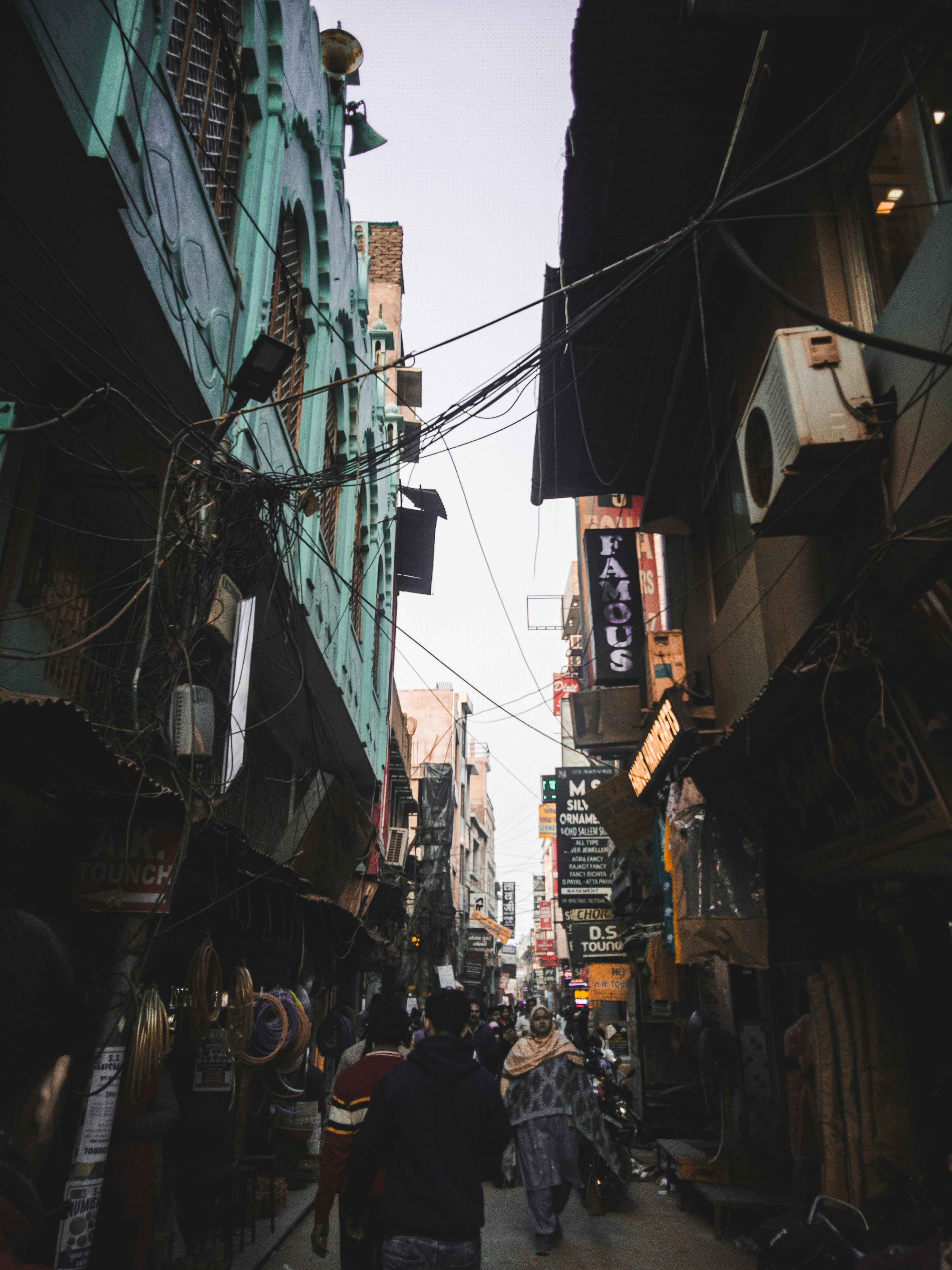 a group of people walking down a street next to tall buildings