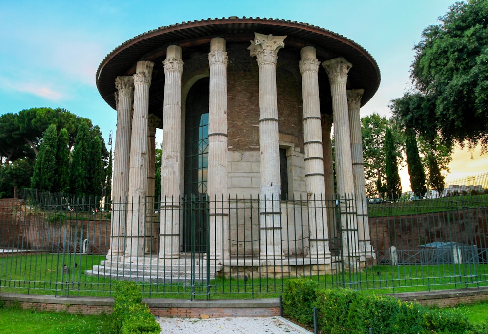 a round building with columns and a fence around it