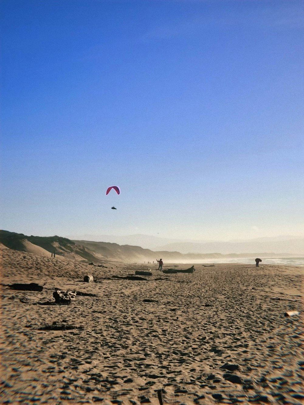 a group of people flying kites on top of a sandy beach