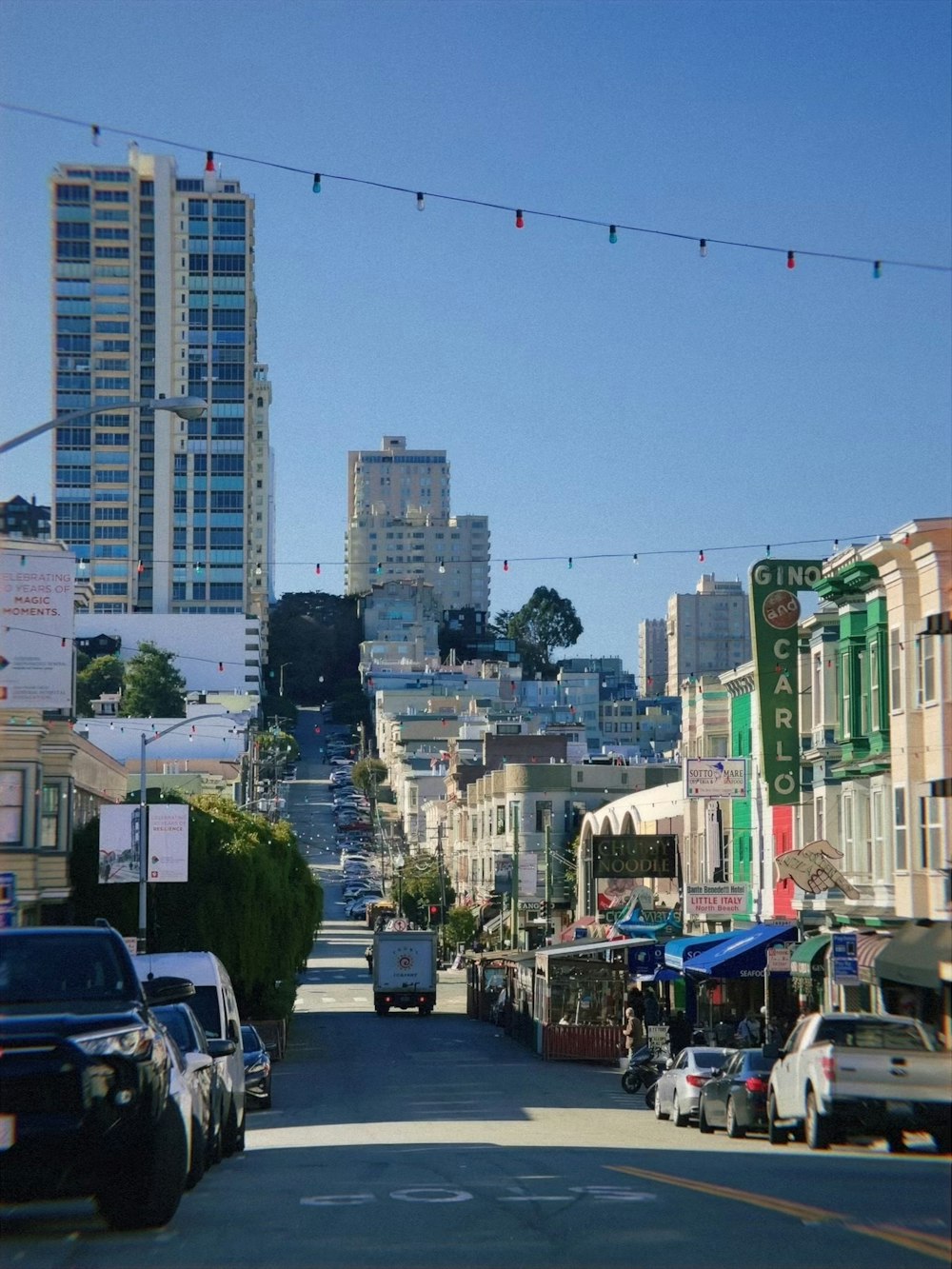 a city street lined with parked cars and tall buildings