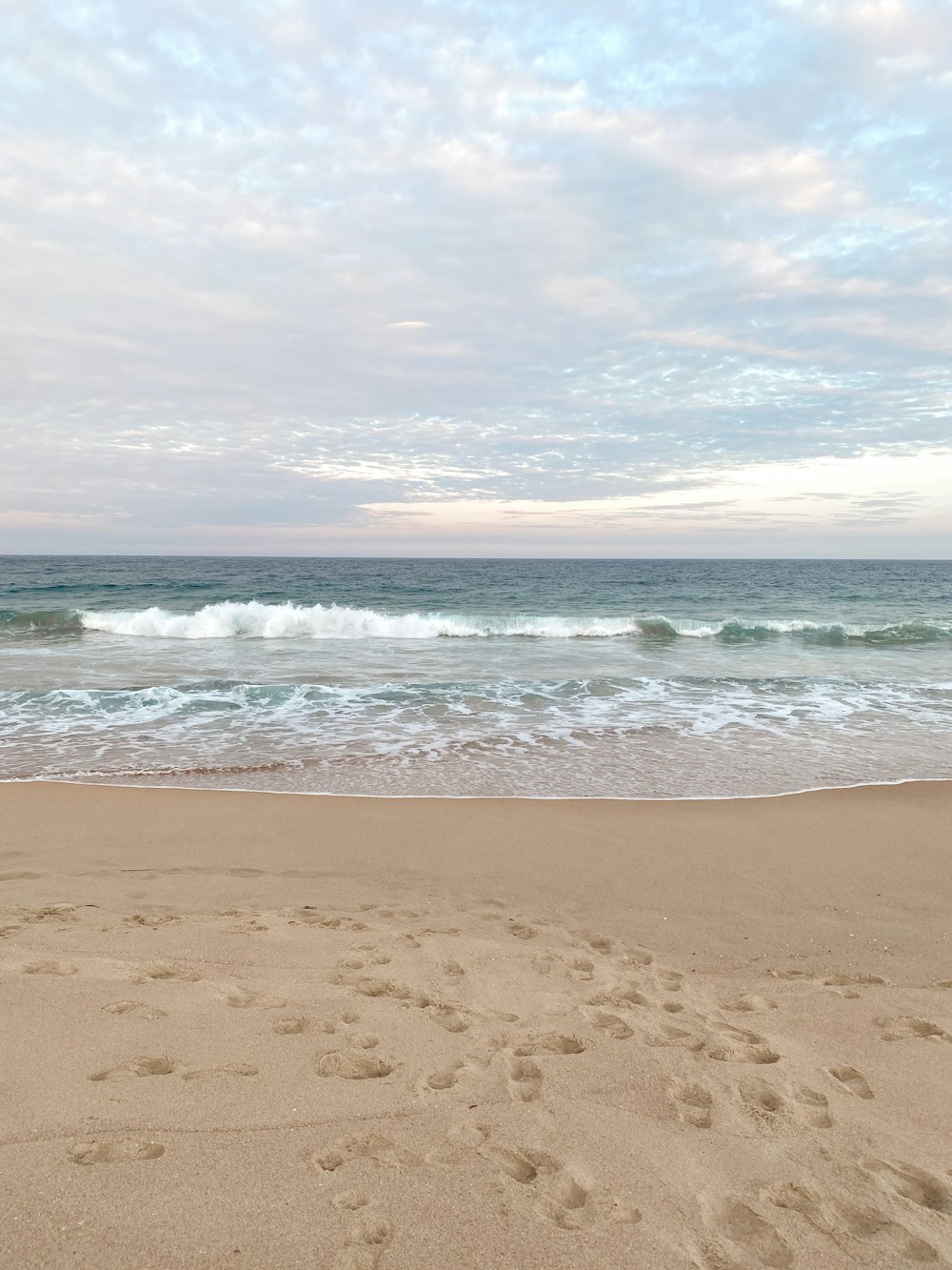 a beach with a surfboard and footprints in the sand