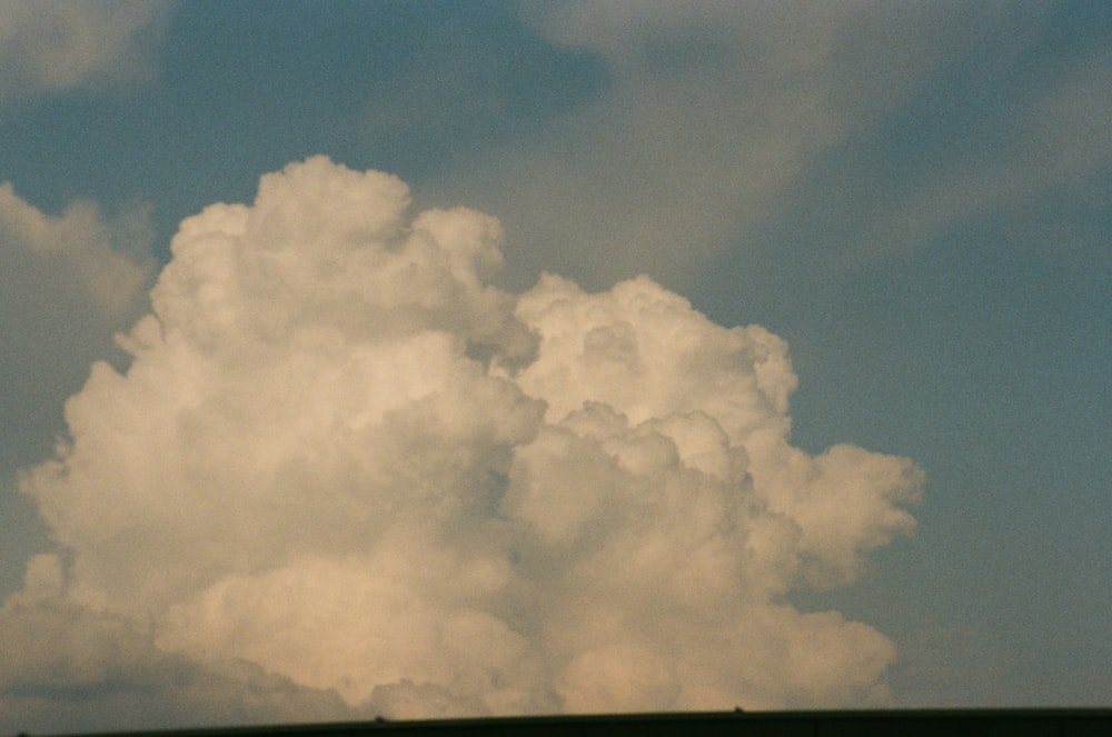 a large cloud is in the sky above a field