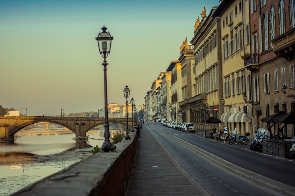 a row of buildings along a river with a bridge in the background