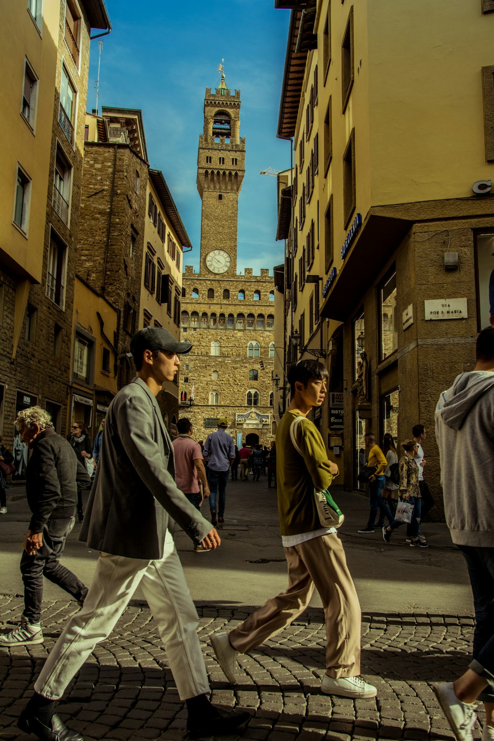 a group of people walking down a street next to tall buildings