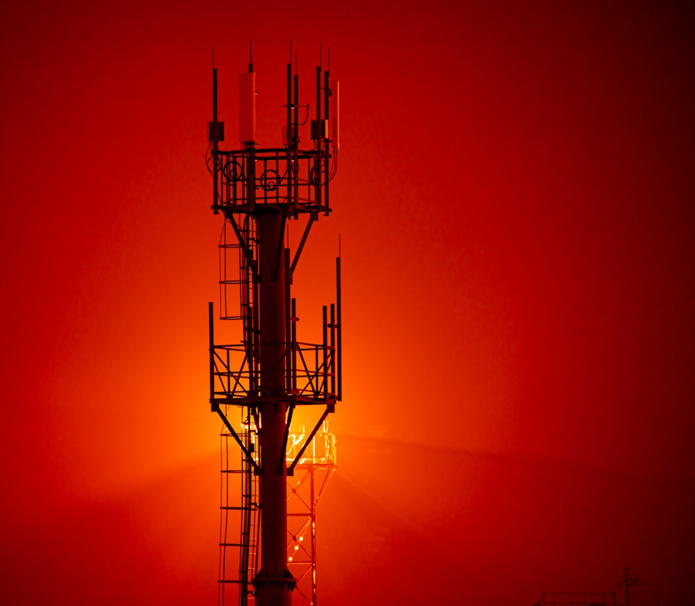 a tall tower sitting next to a red sky