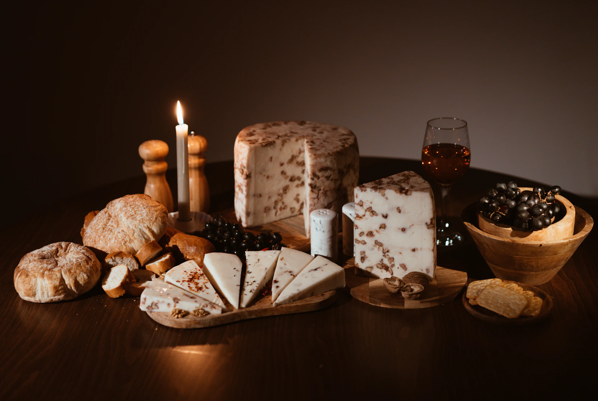 Fromages affinés, pain et vin sur une table éclairée à la bougie