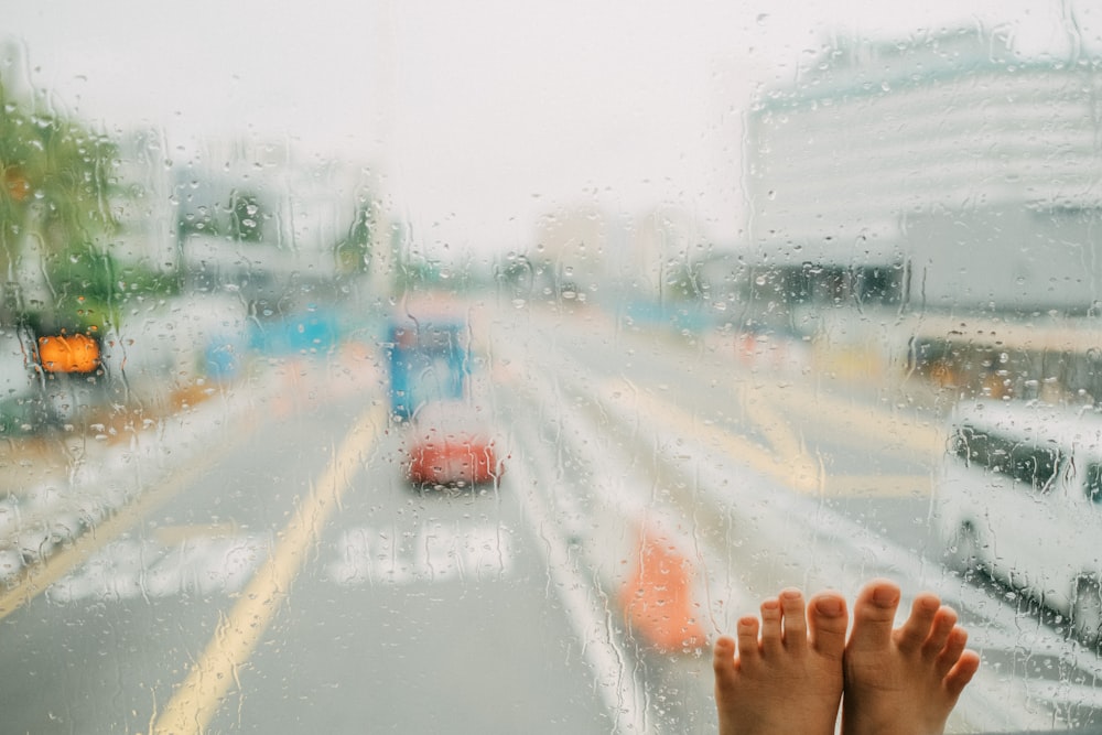 a person's feet sticking out of a window on a rainy day