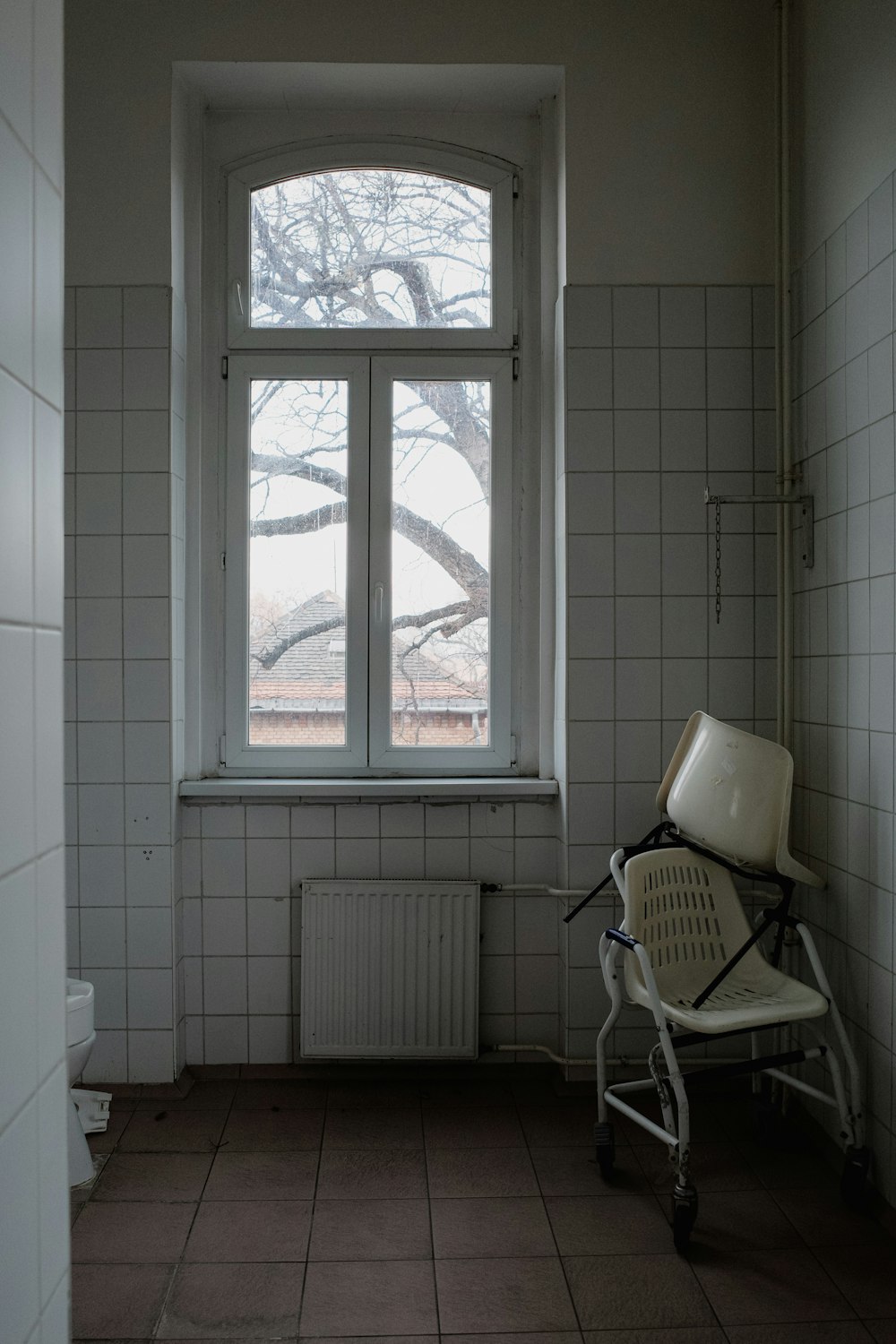 a chair sitting in front of a window in a bathroom