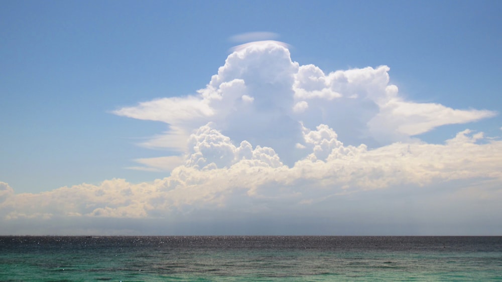 a large cloud in the sky over a body of water