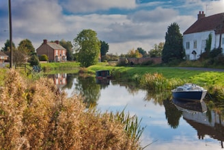 a small boat floating on top of a river next to a lush green field