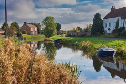 a small boat floating on top of a river next to a lush green field