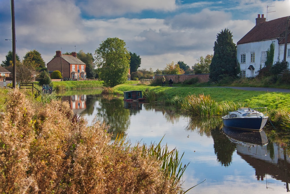 a small boat floating on top of a river next to a lush green field