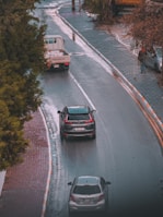 a couple of cars driving down a wet road