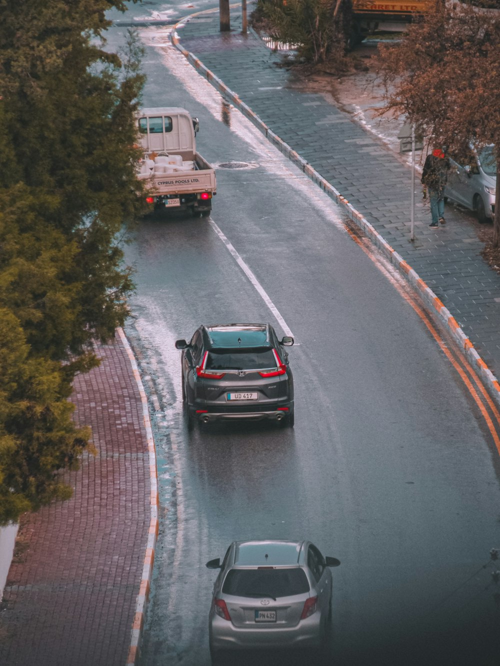 a couple of cars driving down a wet road