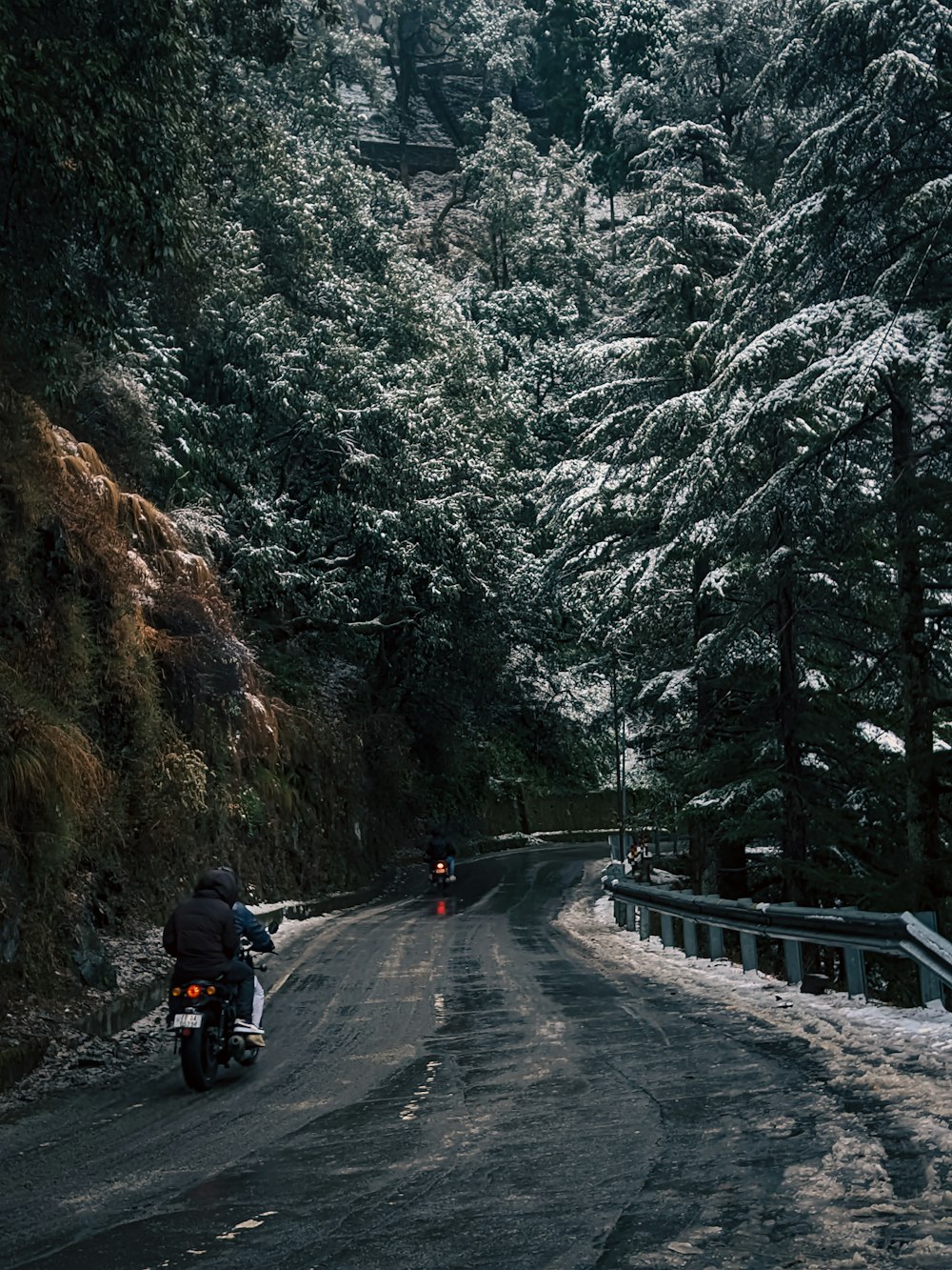 a man riding a motorcycle down a snow covered road