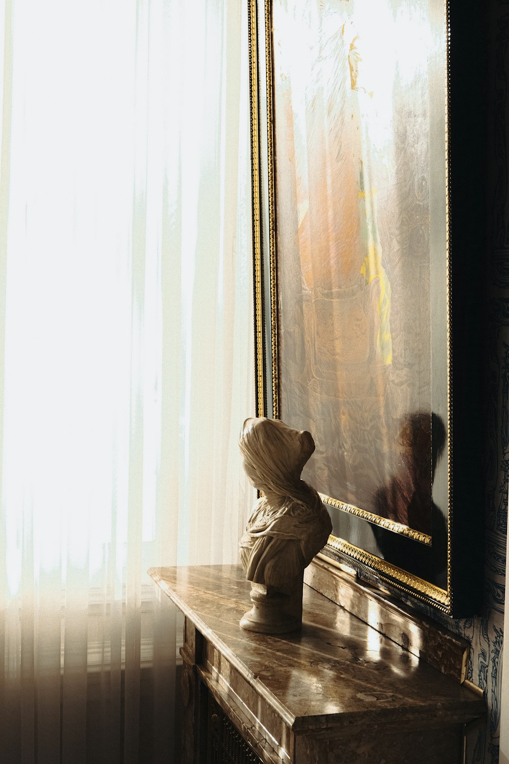 a statue sitting on top of a wooden table next to a mirror