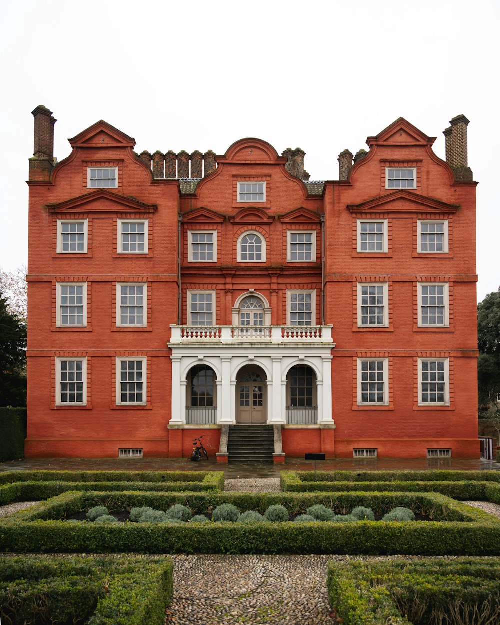 a large red brick building with a garden in front of it