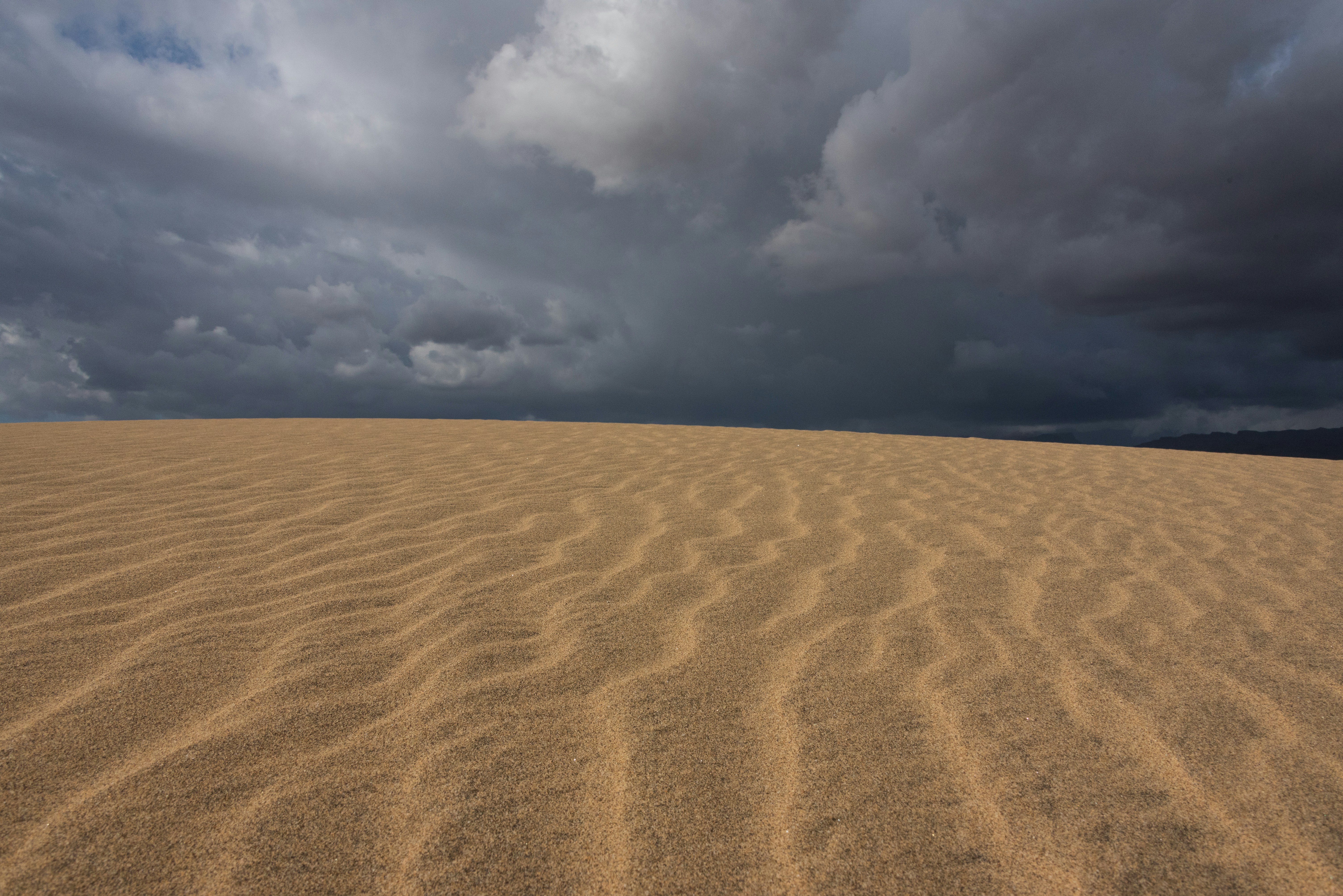 a large sand dune under a cloudy sky, 