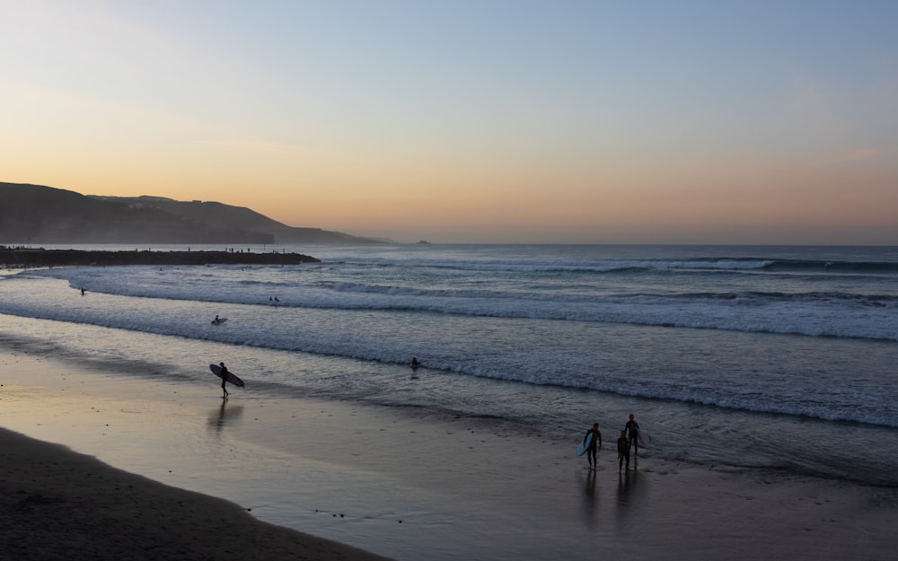 a group of people standing on top of a beach next to the ocean