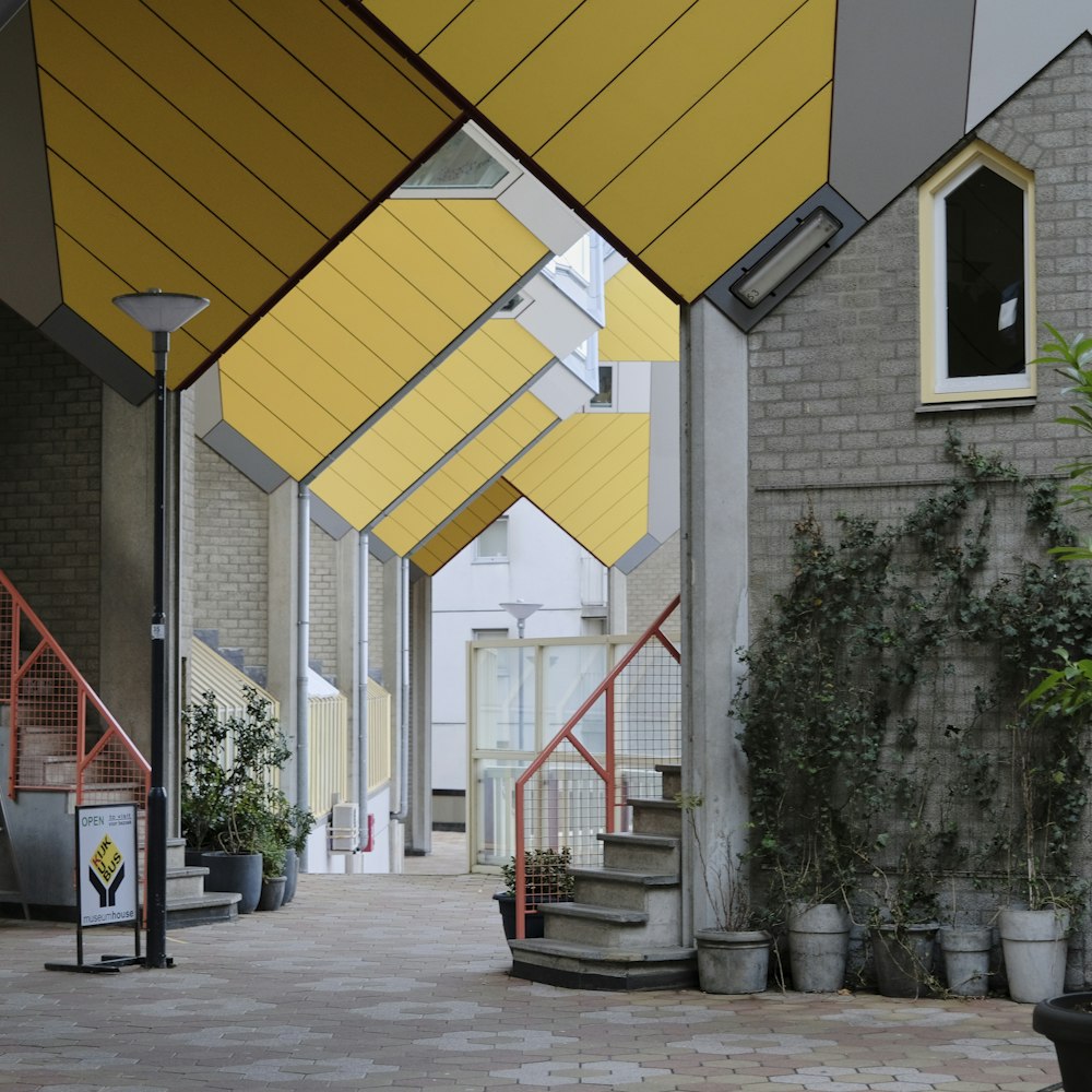 a walkway lined with yellow umbrellas next to a building