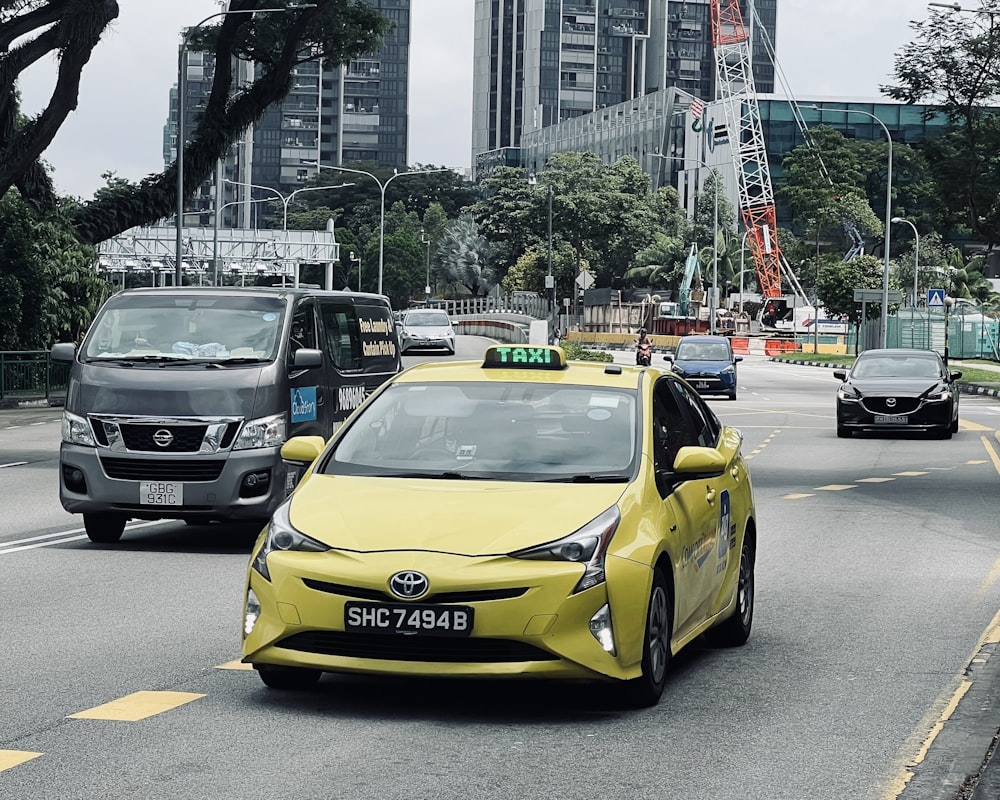 a yellow taxi cab driving down a street next to tall buildings