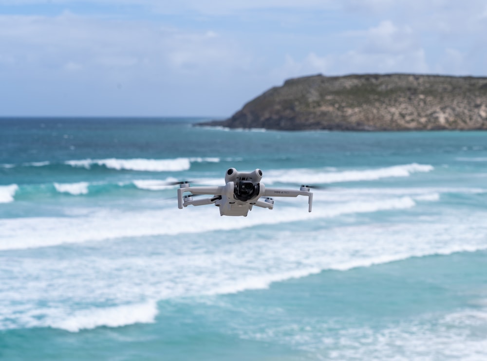 a small white remote controlled flying over the ocean