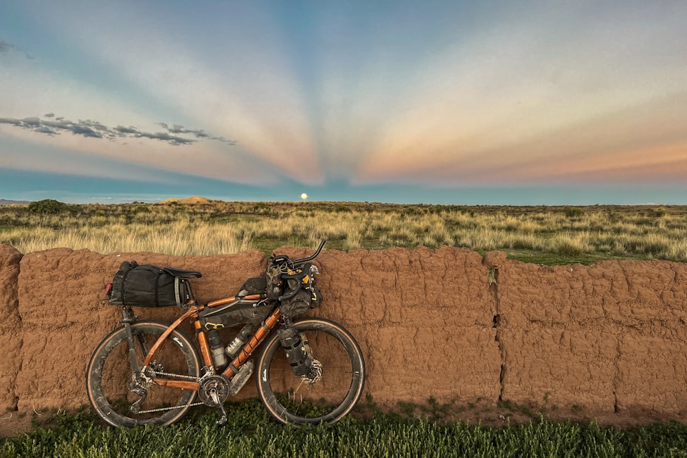 a bike leaning against a wall in a field