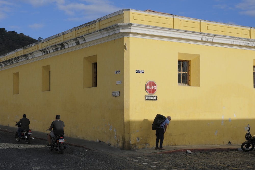 a group of people standing outside of a yellow building