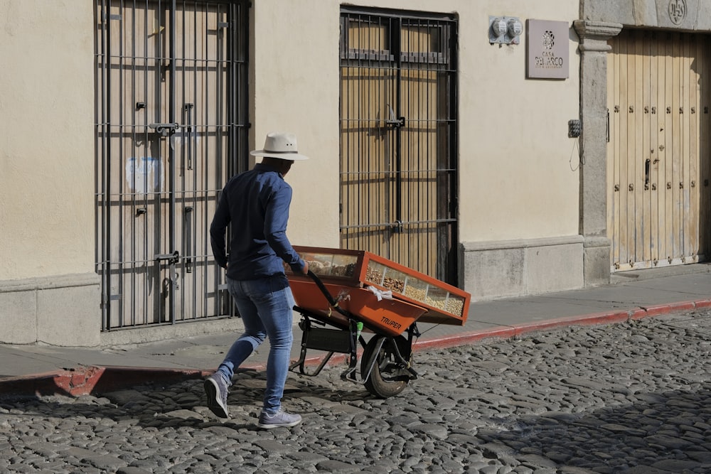a man pushing a wheelbarrow down a street