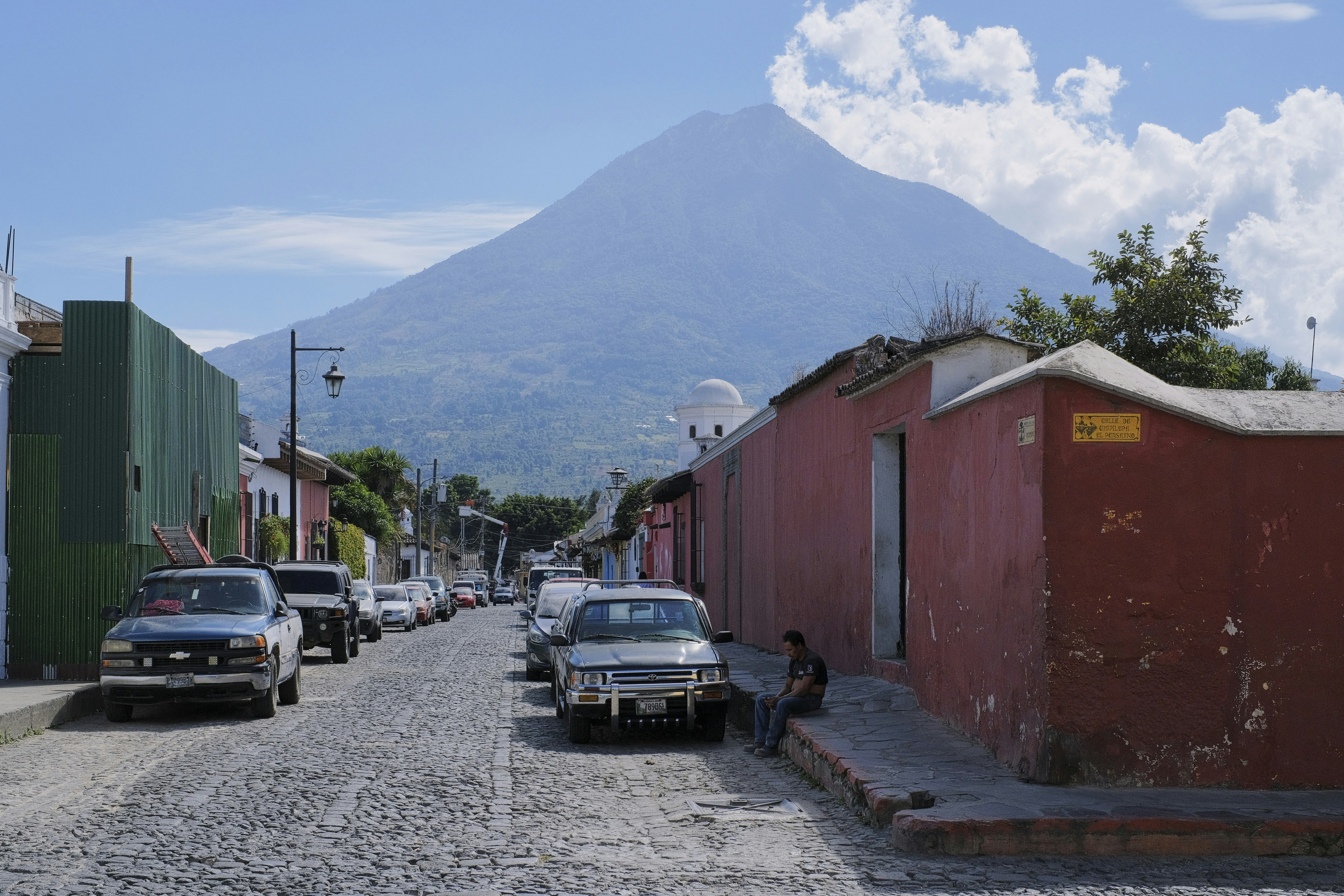 a street with cars parked on both sides and a mountain in the background