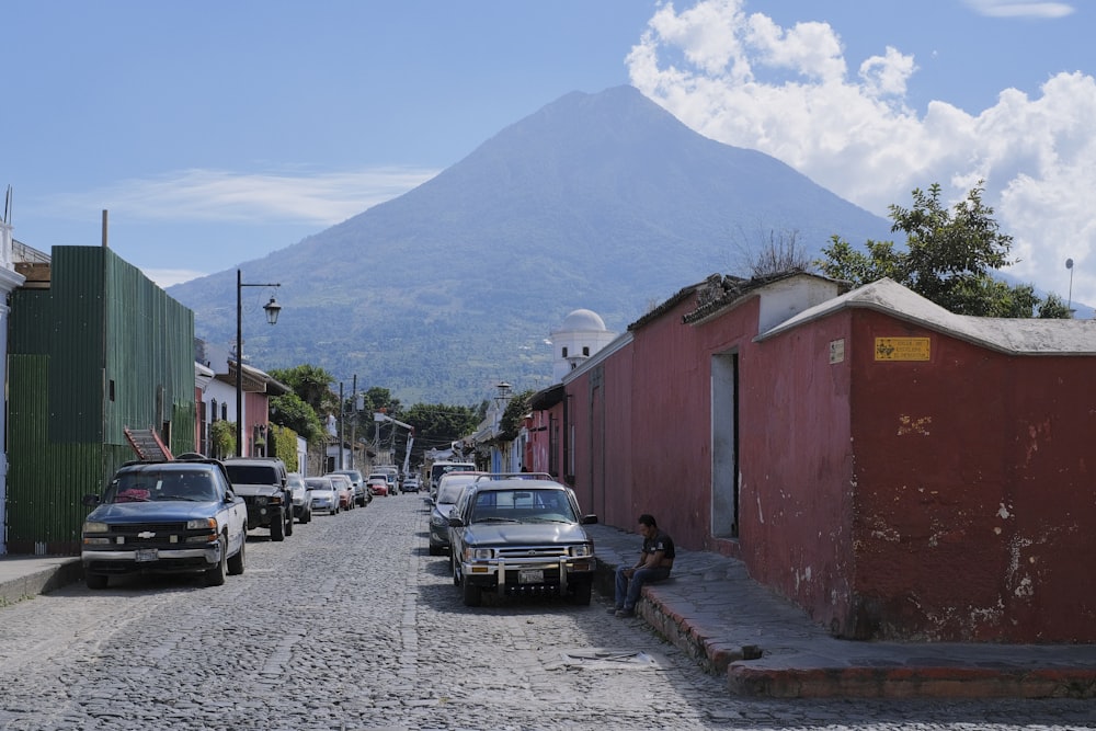 a street with cars parked on both sides and a mountain in the background