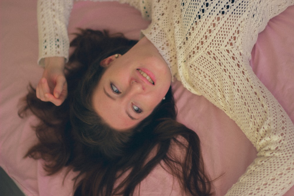 a woman laying on a bed with a pink blanket