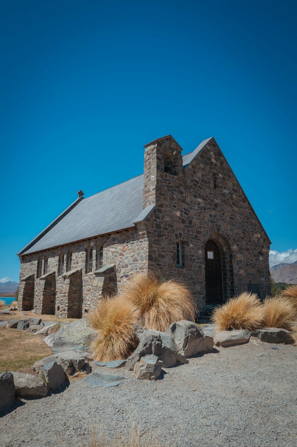 an old stone church with grass and rocks around it
