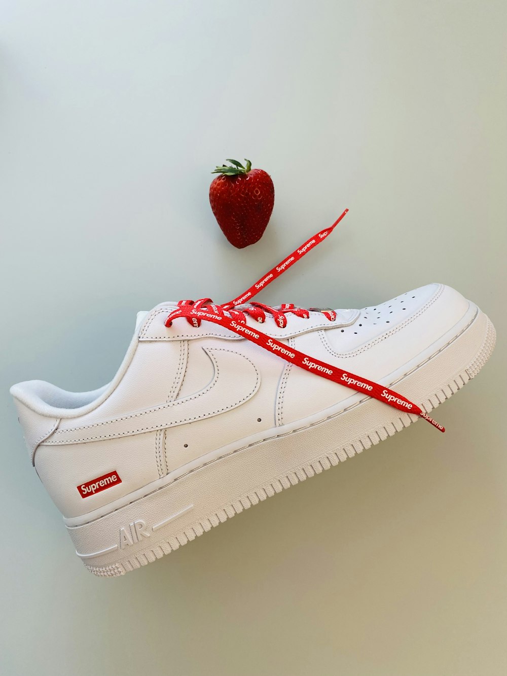 a pair of white sneakers tied to a strawberry