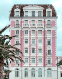 a pink and white building with palm trees in front of it