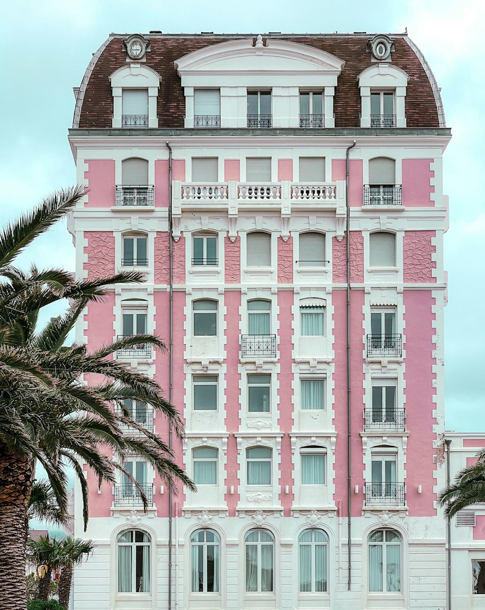 a pink and white building with palm trees in front of it