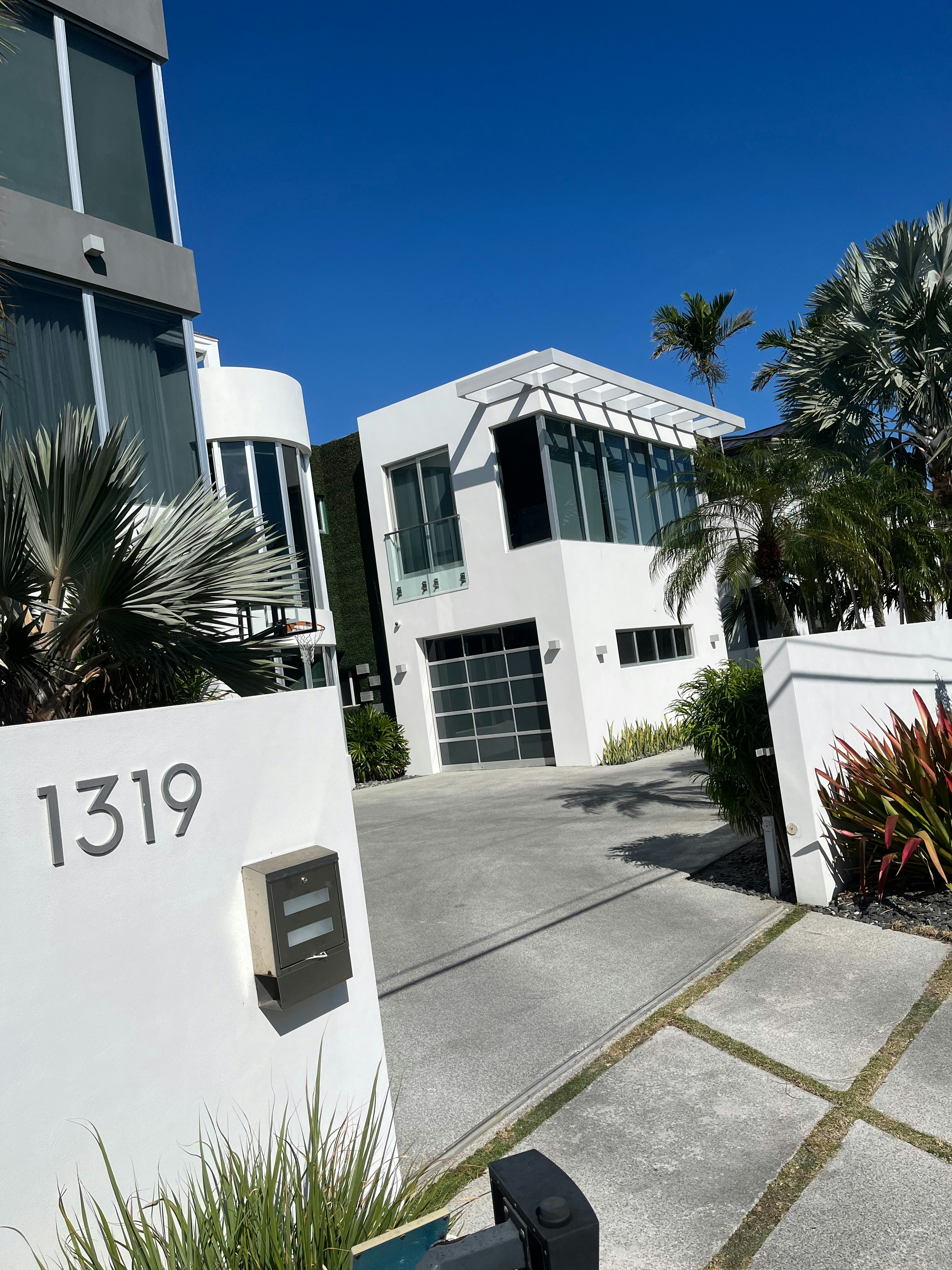 Contemporary white stucco home with manicured lawn and two-car garage in upscale Florida neighborhood