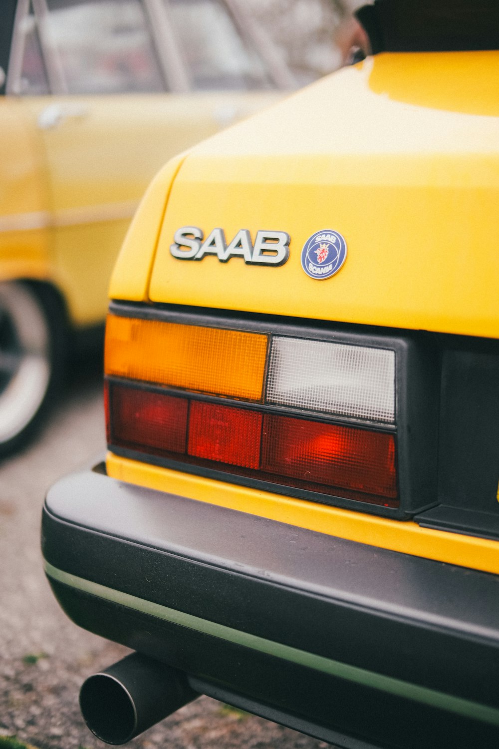 the rear end of a yellow saab car