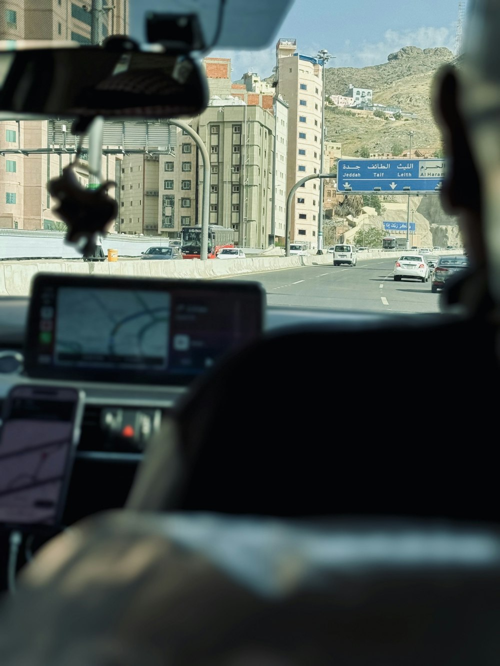 a man driving a car down a street next to tall buildings