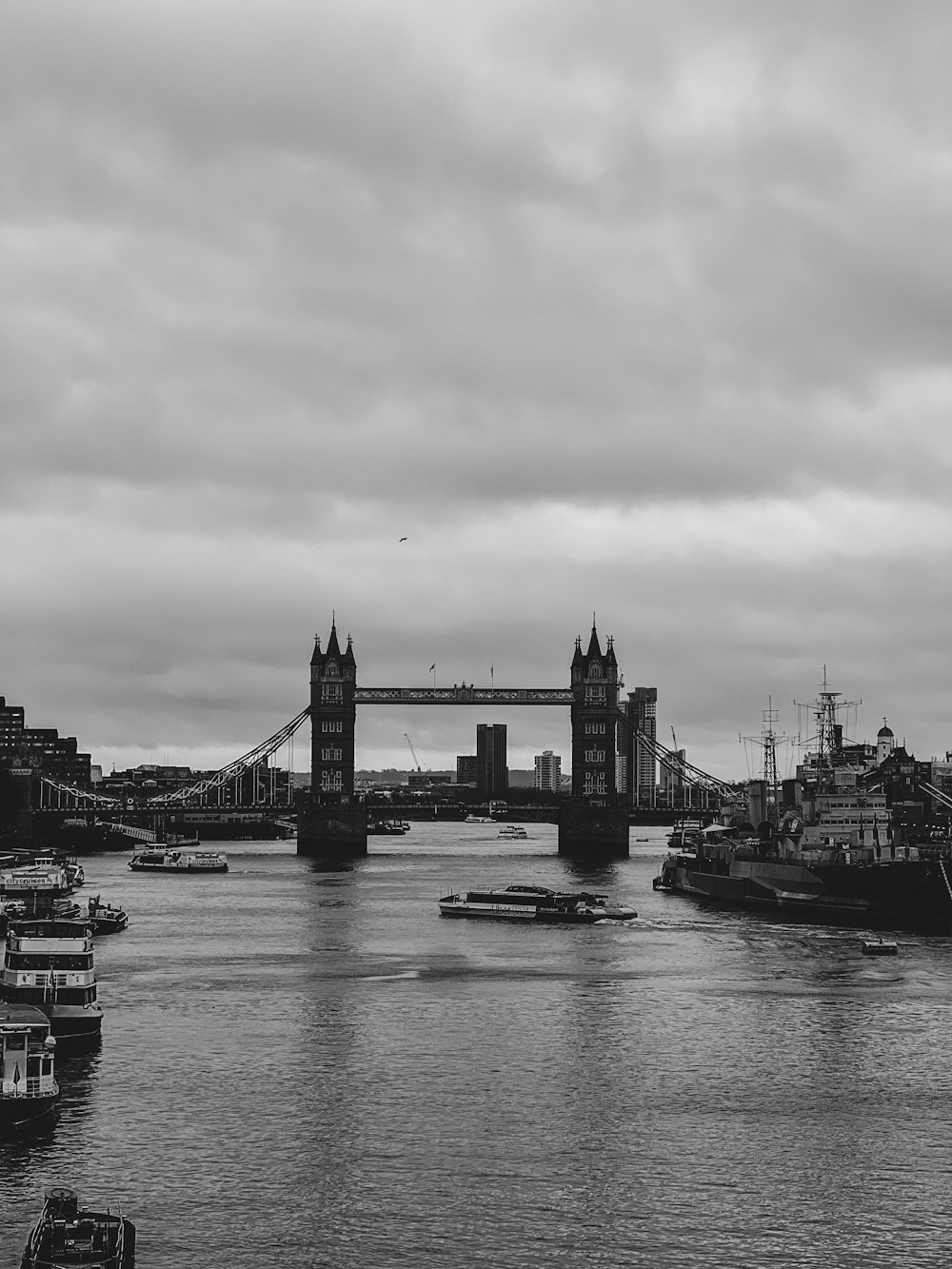 a black and white photo of a bridge and boats