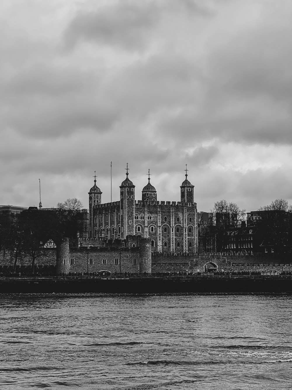 a black and white photo of a castle next to a body of water