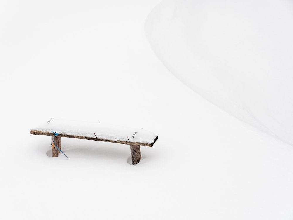 a bench sitting in the middle of a snow covered field