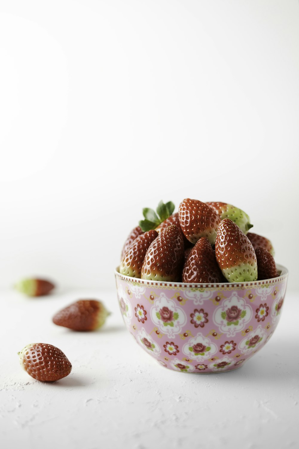 a bowl filled with strawberries on top of a white table