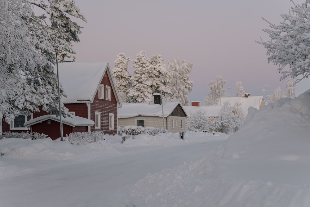 a snow covered street with houses and trees in the background