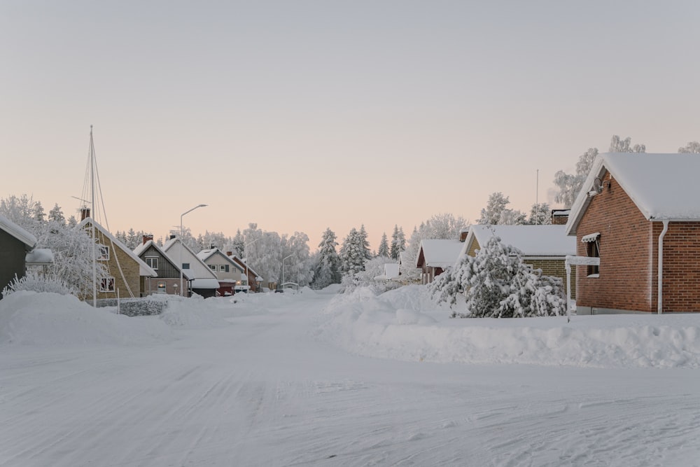 a snow covered street with houses in the background